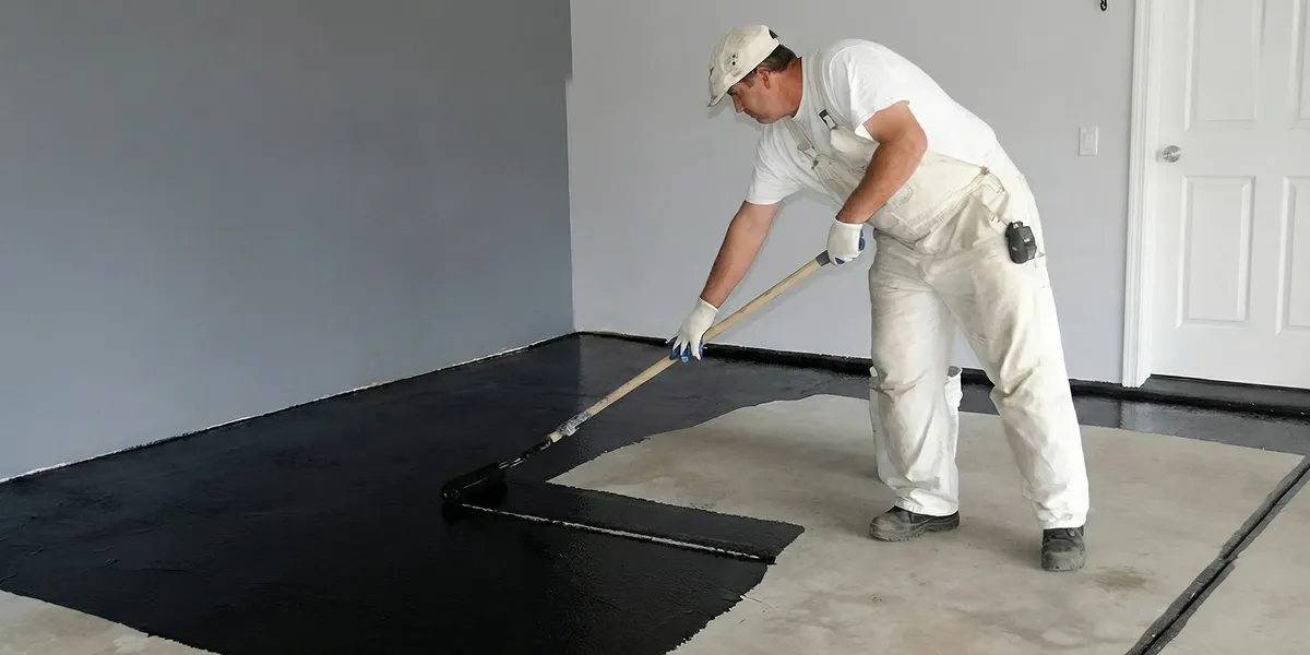 basement waterproofing professional applying waterproof coating to protect a basement floor in Richmond, VA
